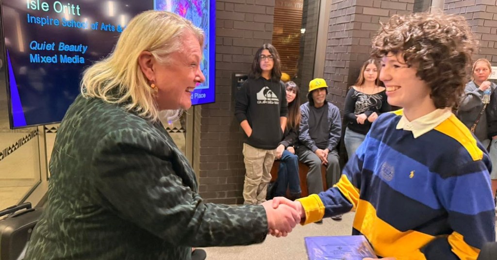 Mary Sakuma congratulates a student with a handshake and a big smile